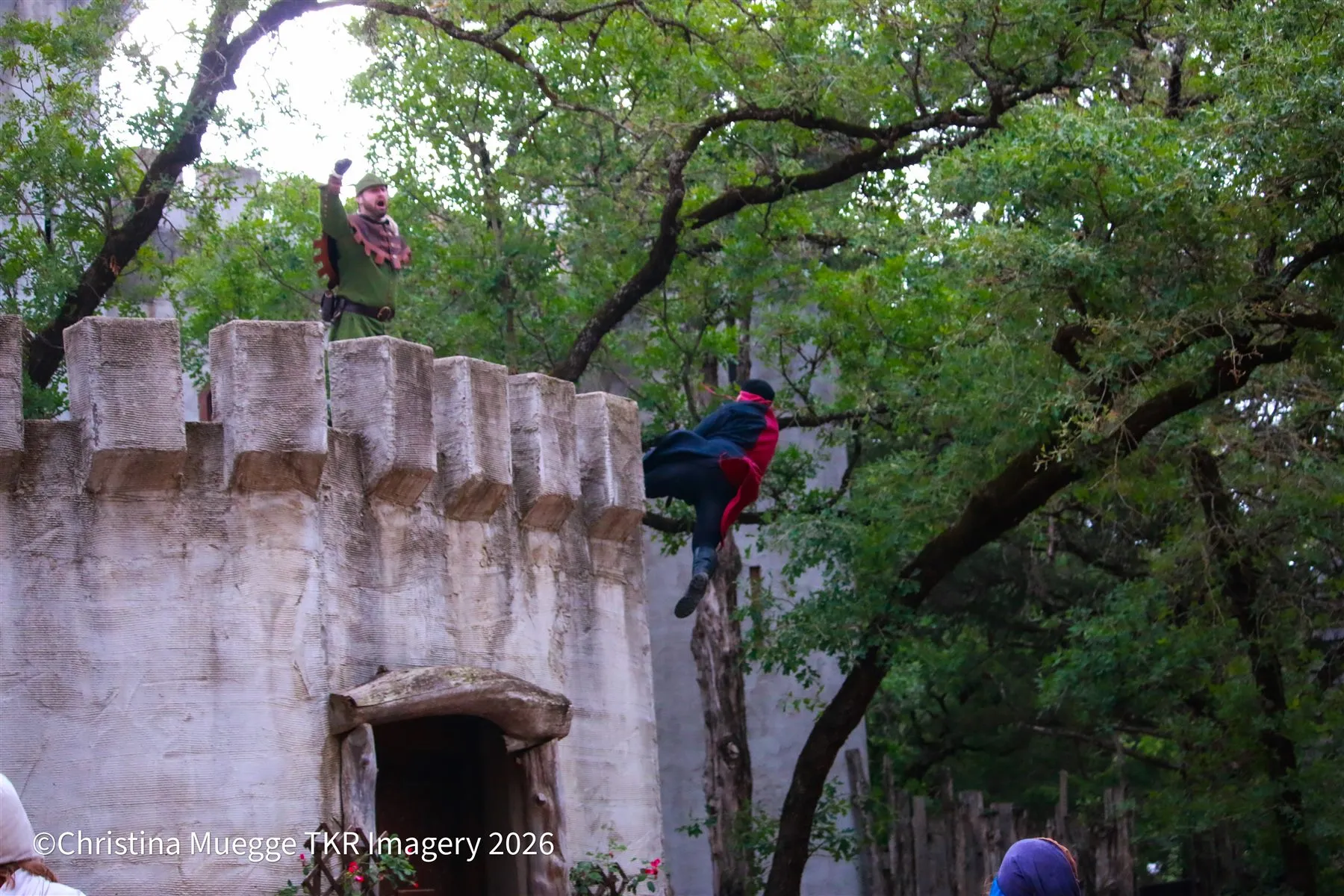 Renaissance festival court performers standing along a castle wall