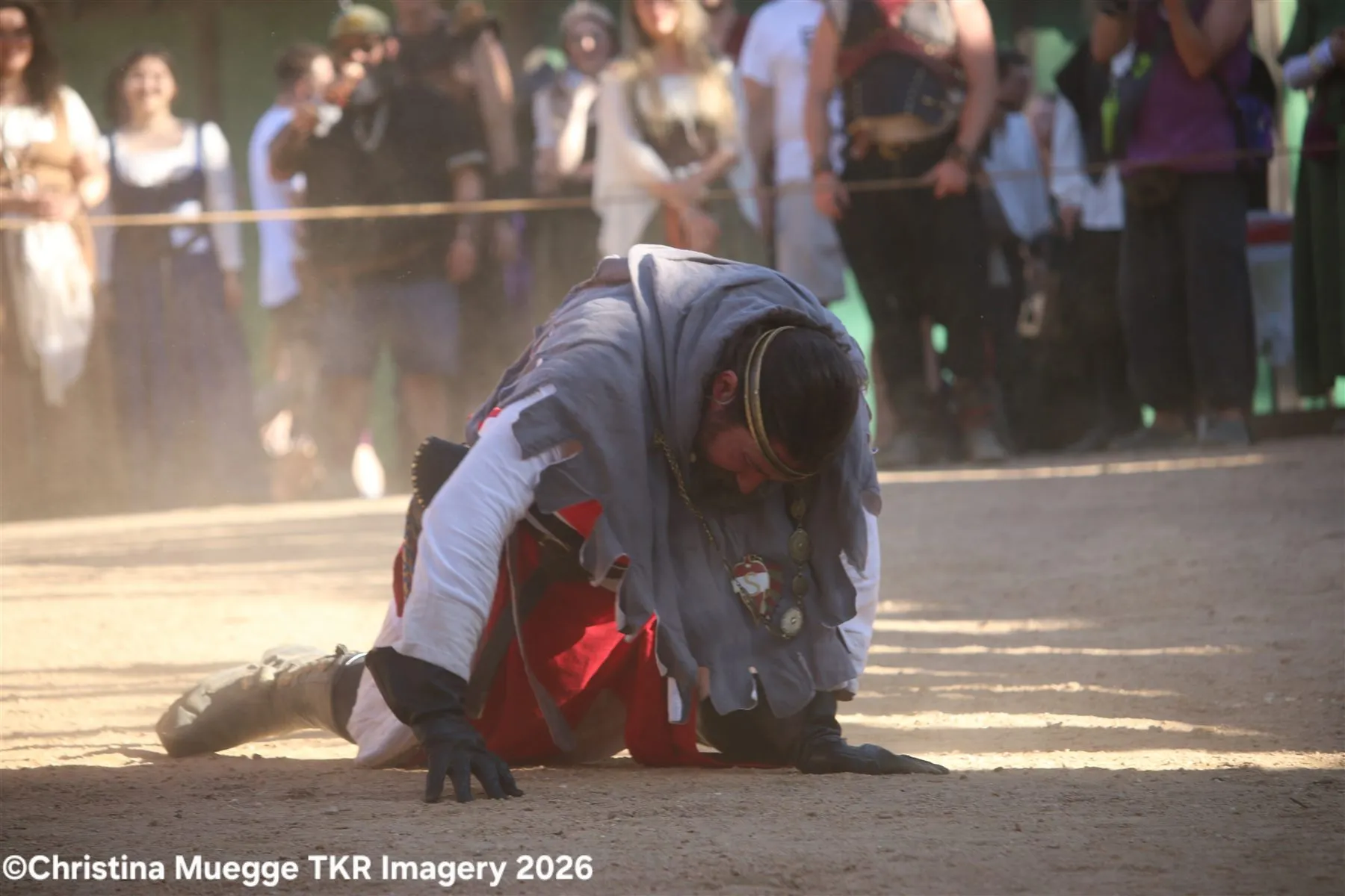 Renaissance festival performer kneeling during an outdoor action scene